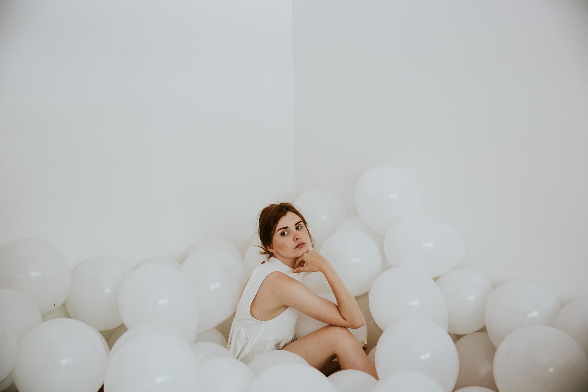 A woman sits among inflated balloons.